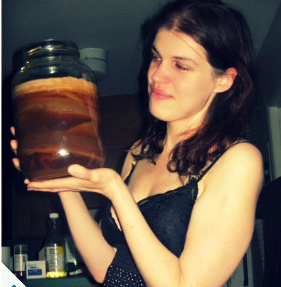 Wilhelmina holding a giant jar of gross looking fermenting tea.